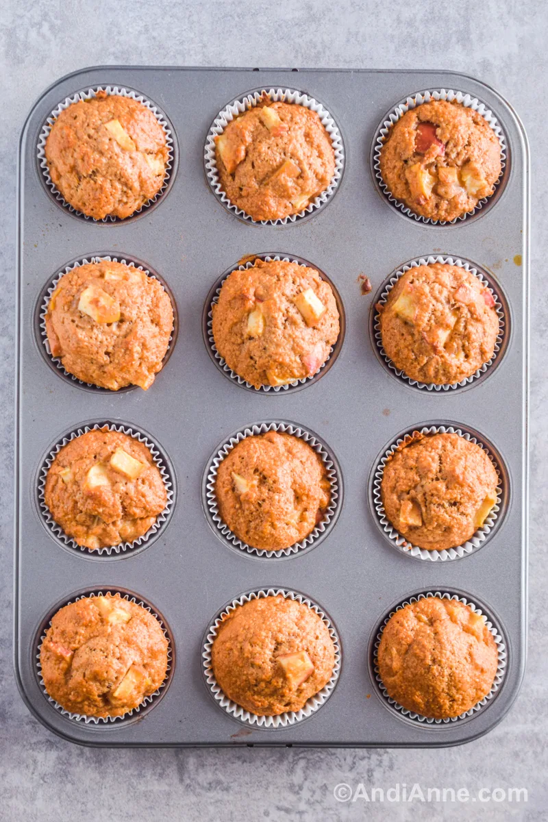 A dozen baked whole wheat apple muffins in a muffin pan.
