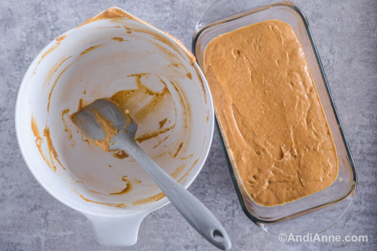 A white bowl and spatula beside a glass loaf pan with batter inside.