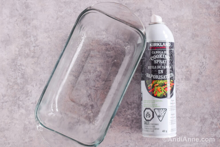 A glass loaf pan and cooking spray on a counter.