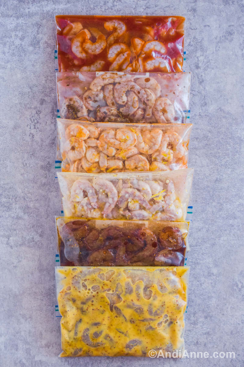 Six ziploc bags full of shrimp in different colored bags piled against eachother on a grey counter.