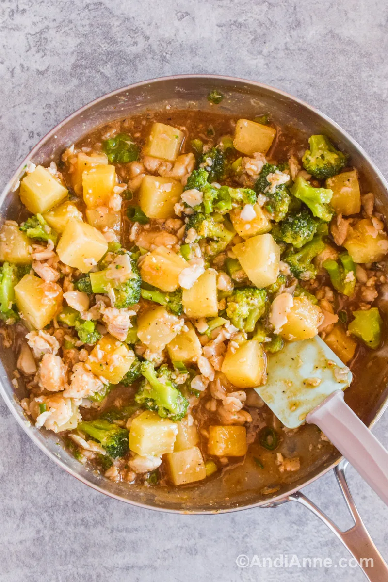 Sweet and sour fish with pineapple and broccoli in a frying pan.
