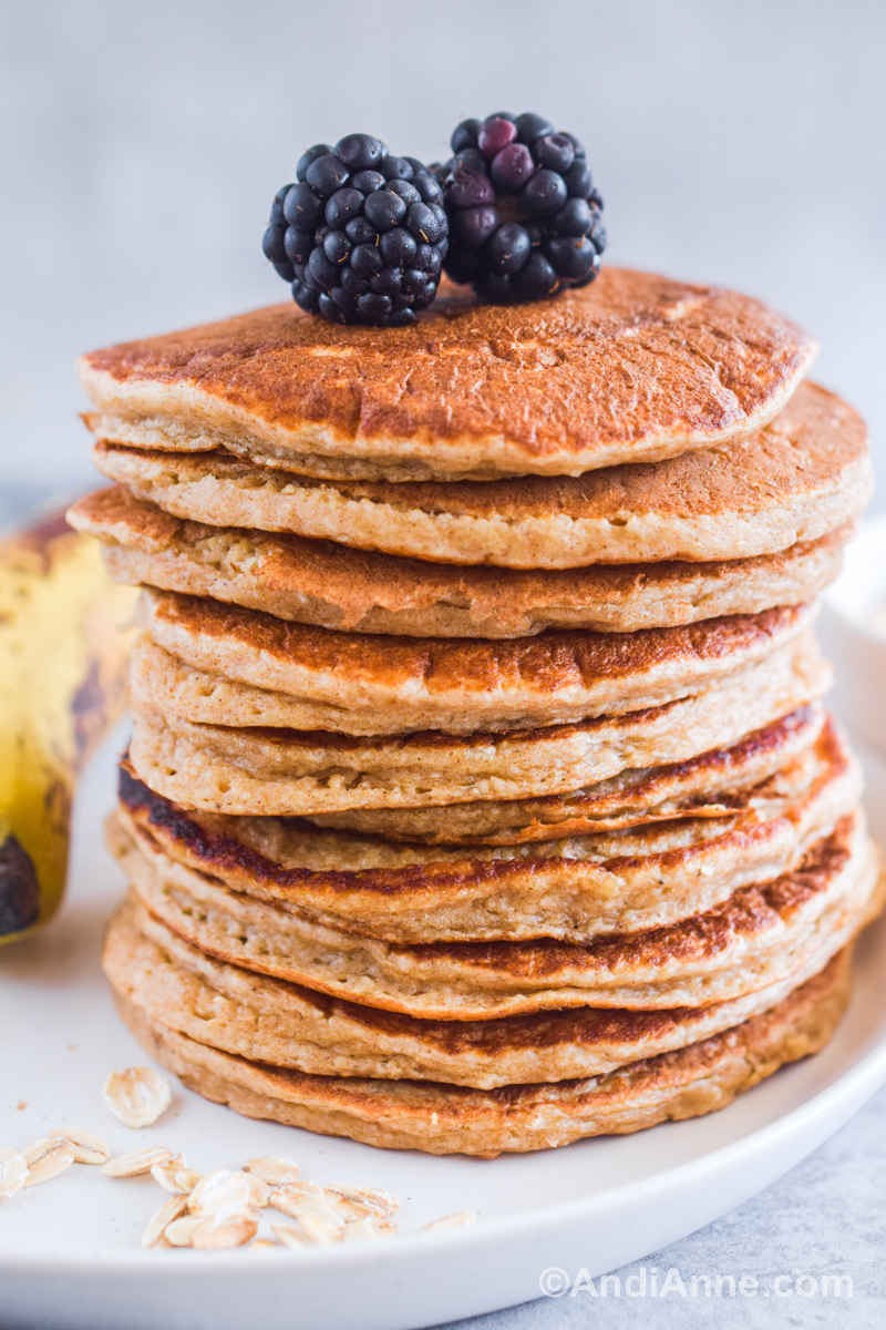 A stack of blender banana oatmeal pancakes with blackberries on top. 