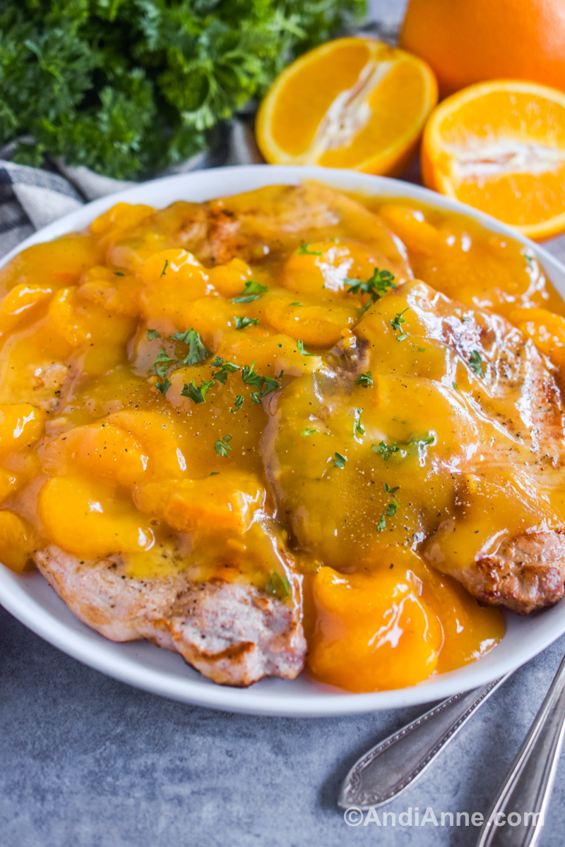 Side angle close up of cooked pork chops with orange sauce on top.