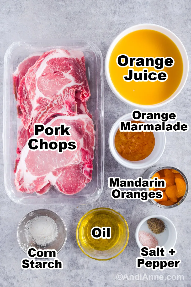 Recipe ingredients on the counter including raw pork chops, and bowls of orange juice, orange marmalade, oil, cornstarch, and canned mandarin oranges.