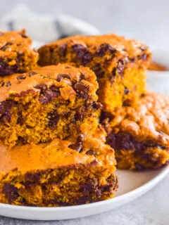 Pumpkin chocolate chip bars stacked on top of each other on a white plate.