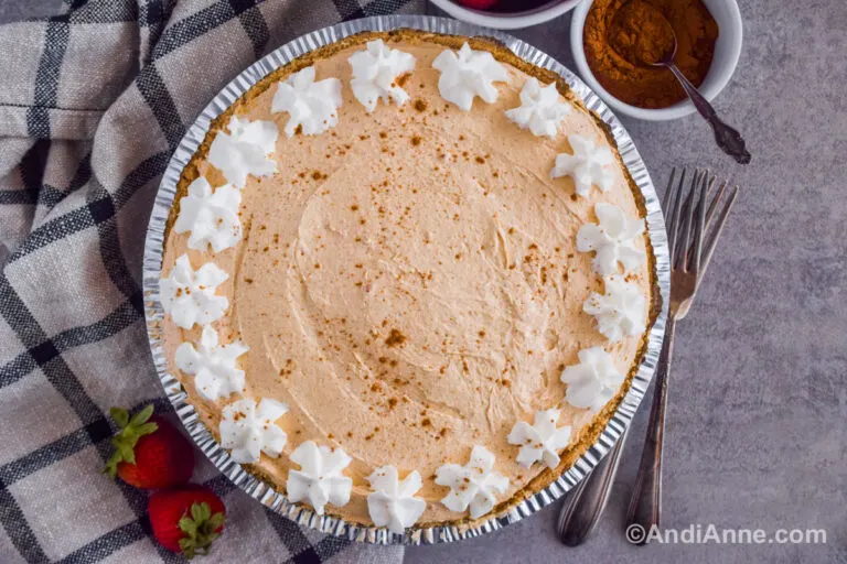 Pumpkin marshmallow pie with dollops of whipped cream on the edges and sprinkle with spice.