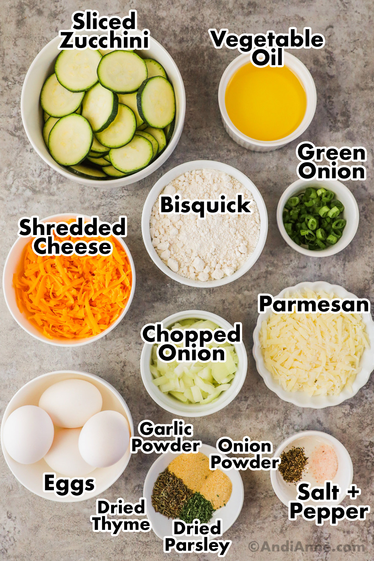 Recipe ingredients in bowls including sliced zucchini, vegetable oil, bisquick, green onion, shredded cheese, chopped onion, eggs, spices and grated parmesan.