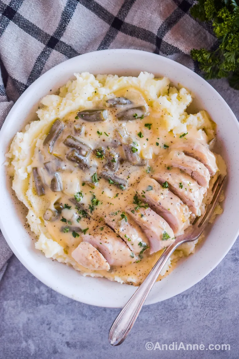 Looking down at mashed potatoes with the cream of chicken and chicken breasts recipe and a fork.