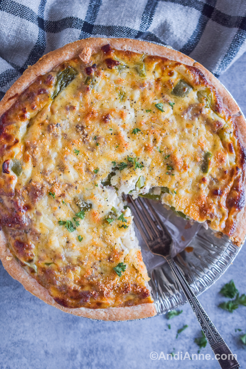 Parmesan ground pork quiche with bell pepper. A slice is taken out and a fork in its place.