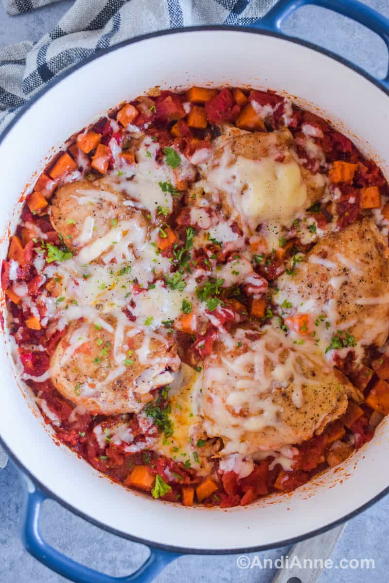 Close up of one pot chicken thighs with sweet potatoes and tomatoes recipe. Melted shredded mozzarella on top.