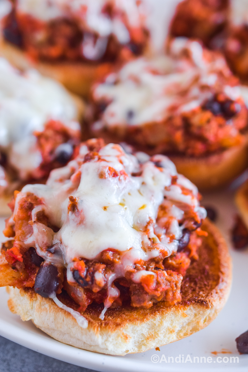 Close up of pizza sloppy joes with melted mozzarella cheese on a white plate.