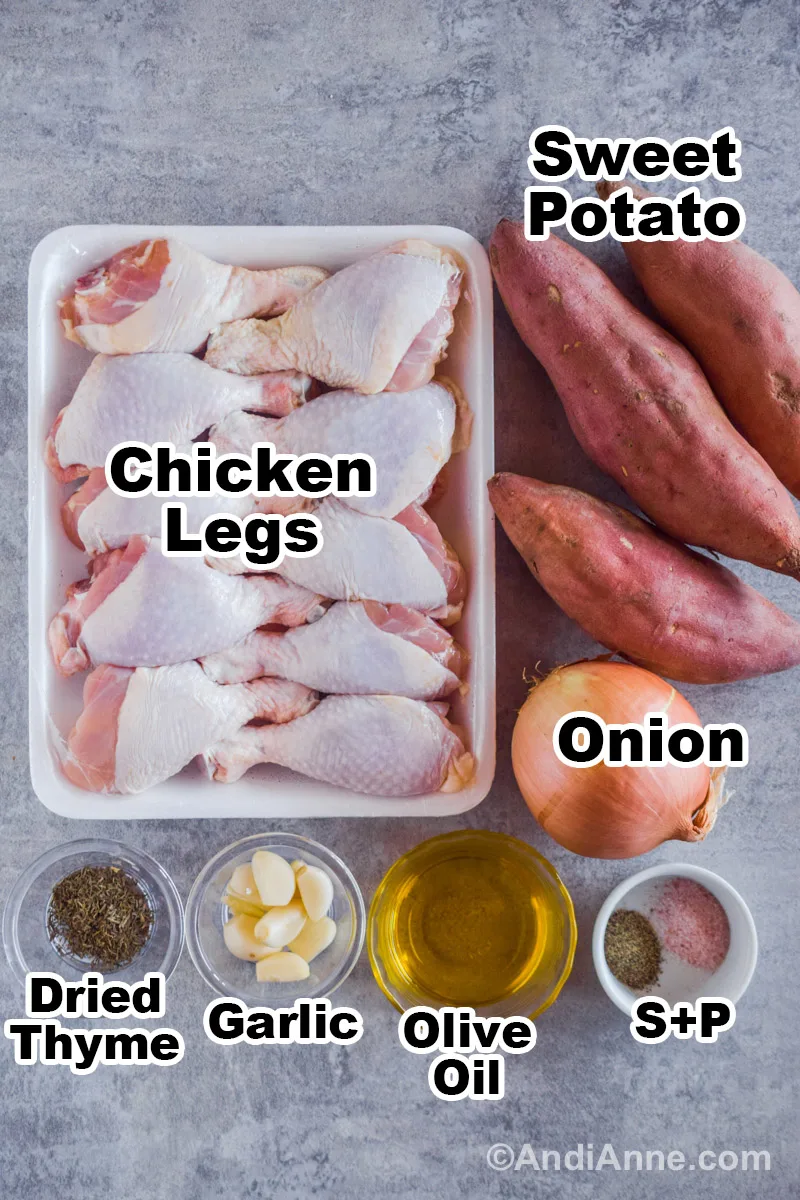 Recipe ingredients on the counter including a container of raw chicken legs, some sweet potatoes, a yellow onion, and bowls of dried thyme, garlic cloves, olive oil, salt and pepper.