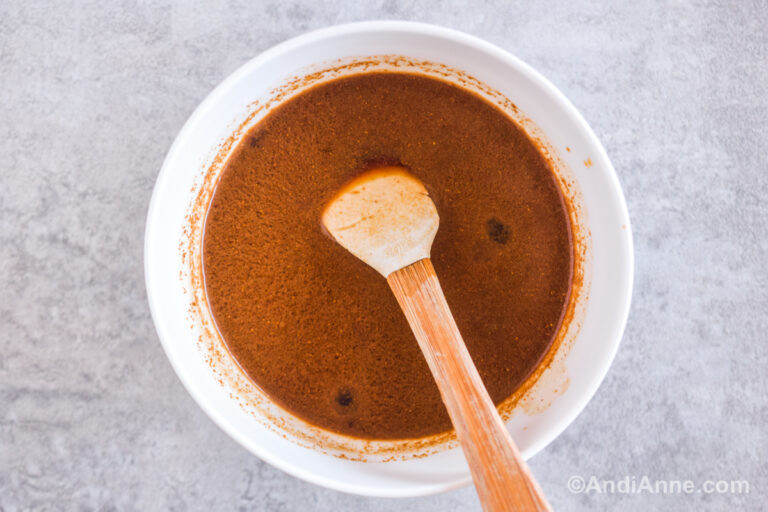 A bowl of brown sauce with a small spoon.