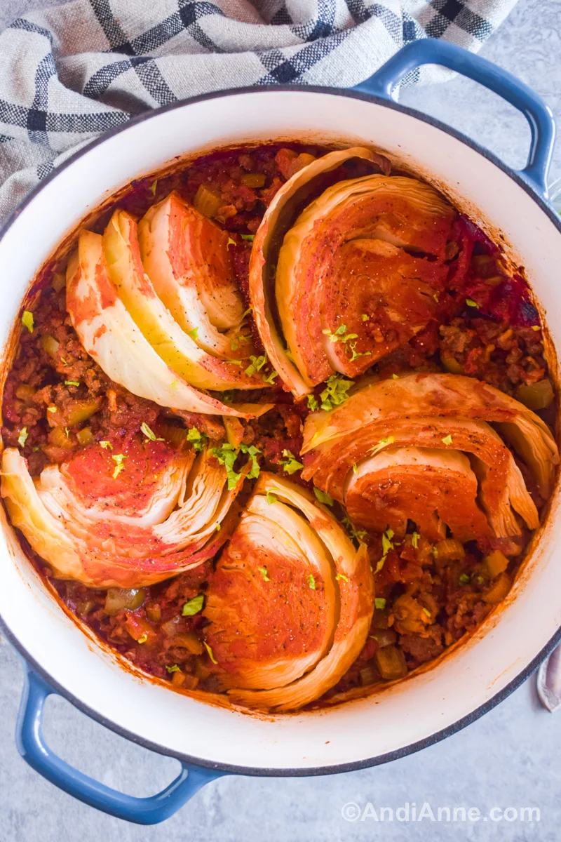 A white pot with cabbage wedges and ground beef mixture inside.