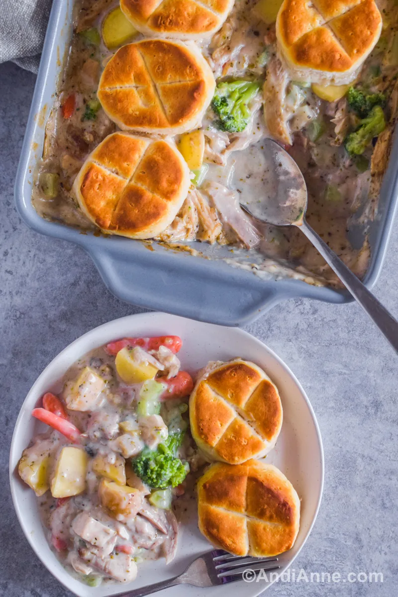 Close up of chicken pot pie recipe on a white plate with casserole dish, a spoon and rest of recipe inside it.