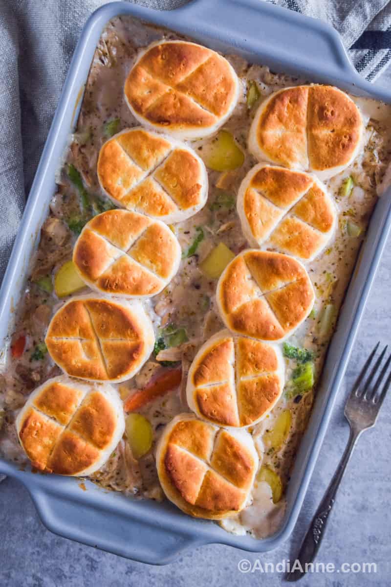 Chicken pot pie casserole recipe in a grey baking dish with golden biscuits on top.