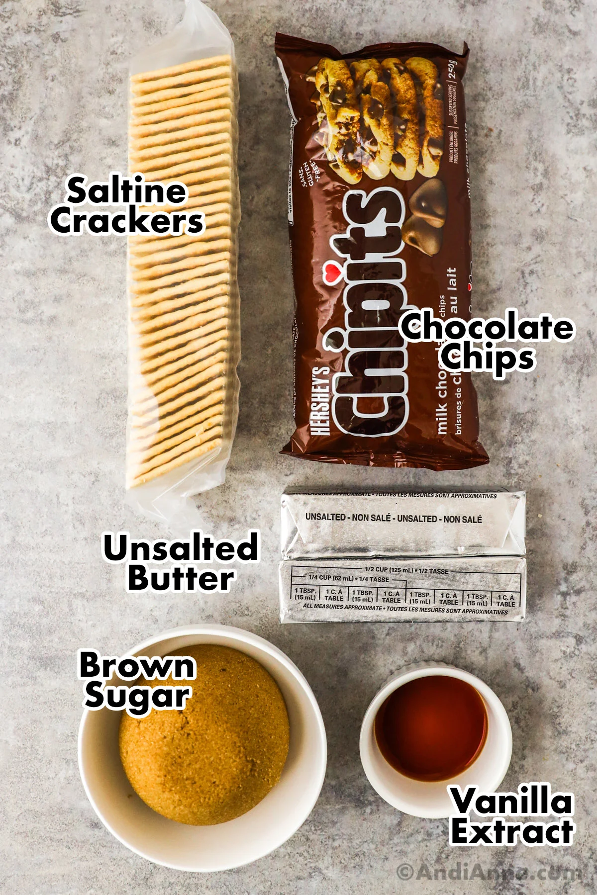 Recipe ingredients including a bag of saltine crackers, bag of chocolate chips, bowl of brown sugar, vanilla extract and unsalted butter sticks.