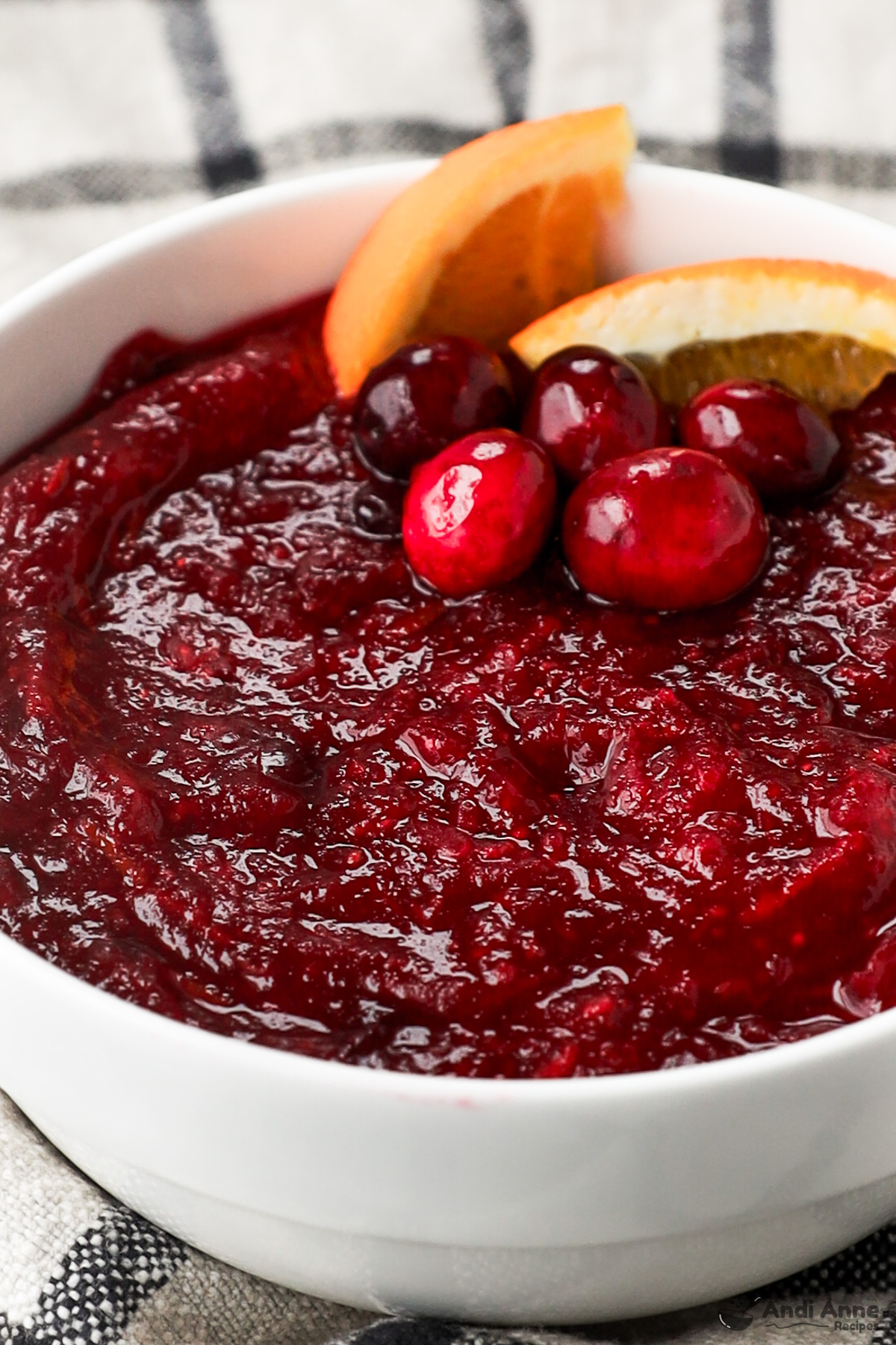 Close up of a bowl cranberry sauce with fresh cranberries accenting and slices of oranges