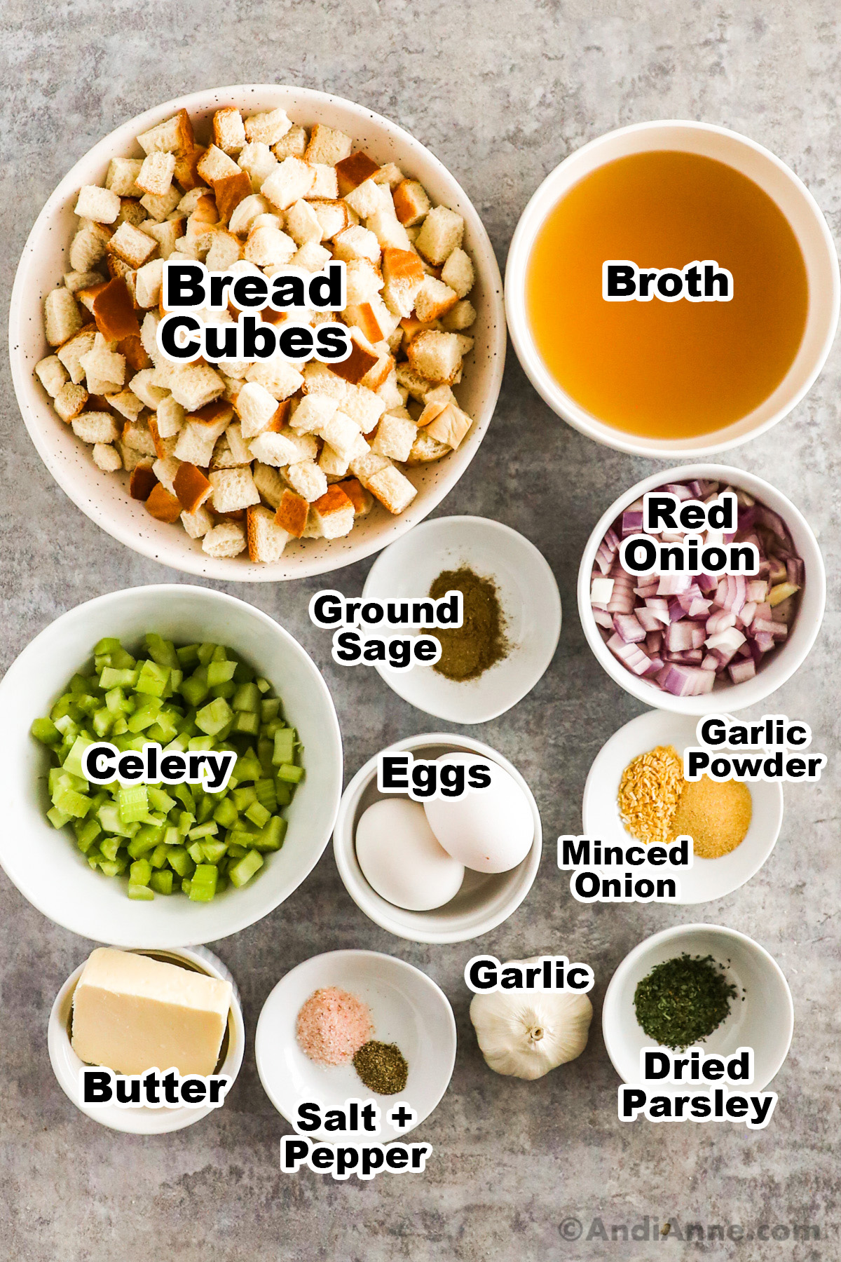Recipe ingredients on counter including bowl of bread crumbs, bowls of broth, chopped celery, red onion, spices, eggs, garlic and butter.