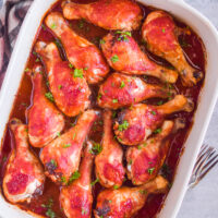 sweet and sour chicken legs in a white casserole dish