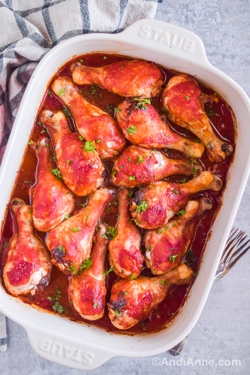 Baked sweet and sour chicken legs in a white casserole dish.