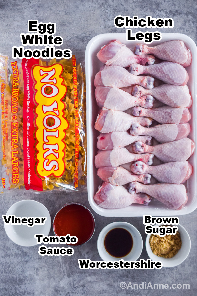 Recipe ingredients including a bag of egg noodles, raw chicken legs, and bowls of white vinegar, worcestershire and brown sugar, plus a can of tomato sauce.