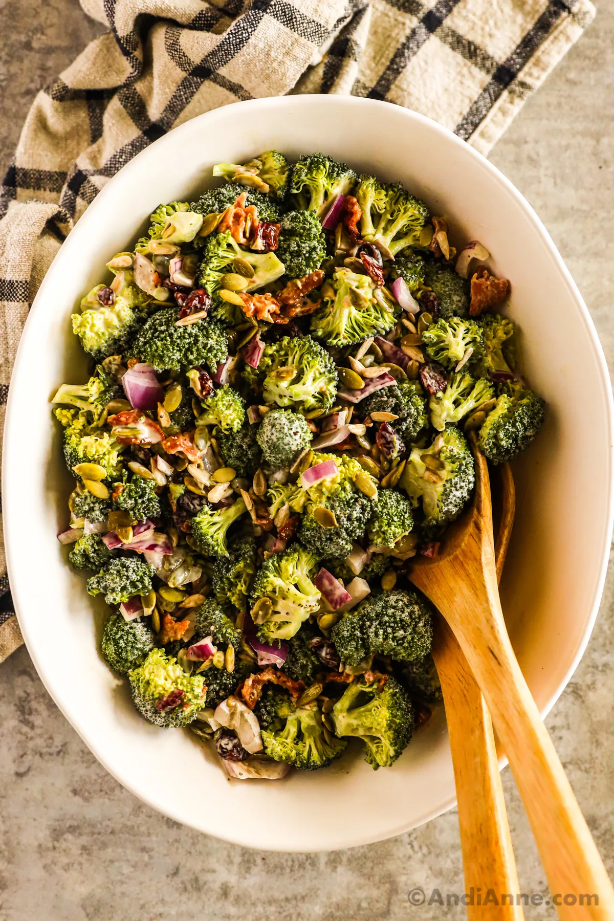 Broccoli crunch salad in a white bowl with wood spoons.