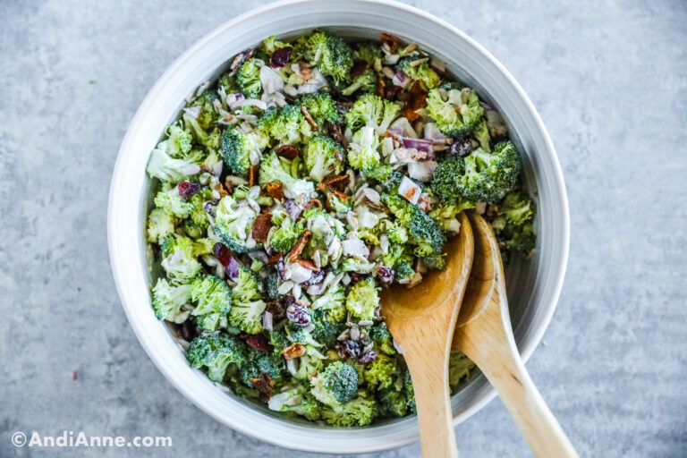 Broccoli crunch salad in a white bowl with wood serving spoons.