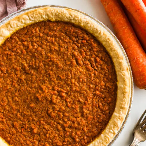 Carrot pie with forks and real carrots beside it.