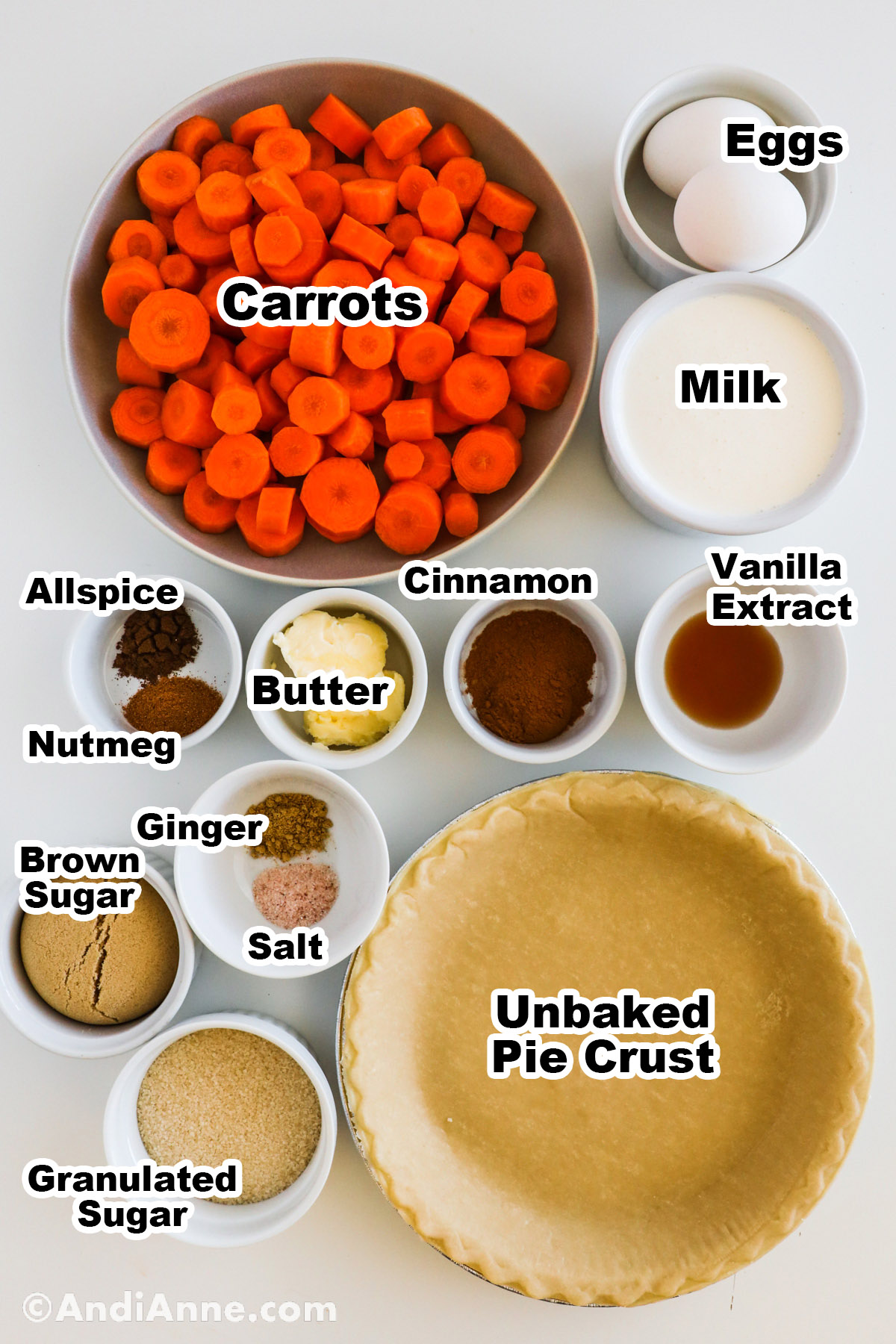 Recipe ingredients on the counter including bowls of milk, egg, spices, chopped carrots, and an empty pie shell. 