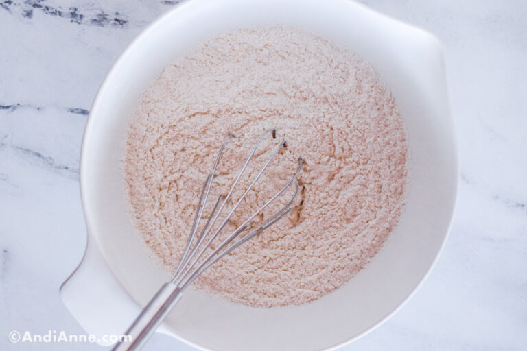 White bowl with flour and a whisk.