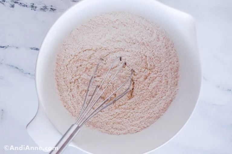 White bowl with flour and a whisk.
