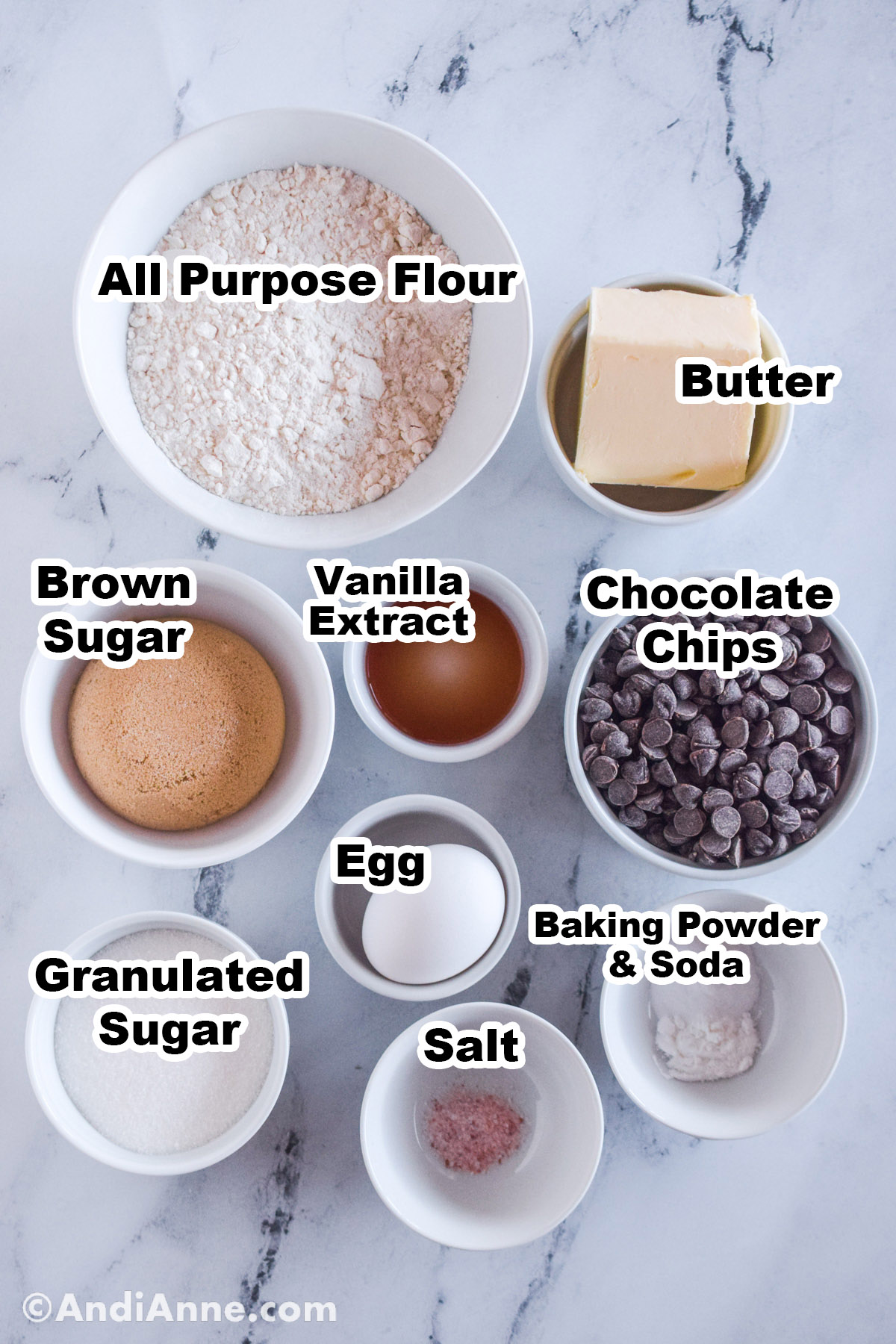 Recipe ingredients in bowls including all purpose flour, butter, brown sugar, vanilla extract, chocolate chips, egg, sugar, salt and baking powder.