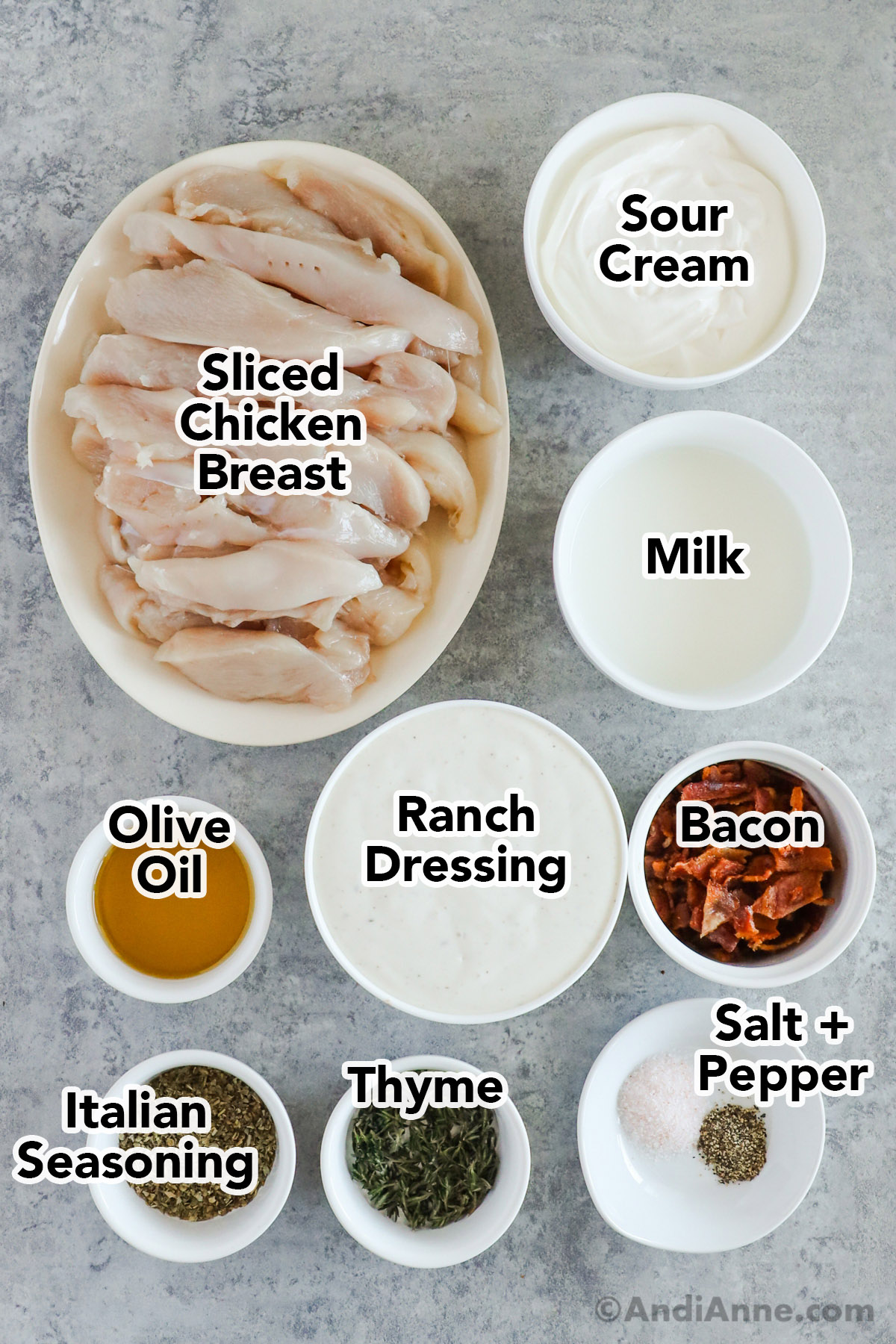 Recipe ingredients in bowls including sliced chicken, sour cream, milk, olive oil, ranch dressing, crumbled bacon, italian seasoning, thyme, salt and pepper.