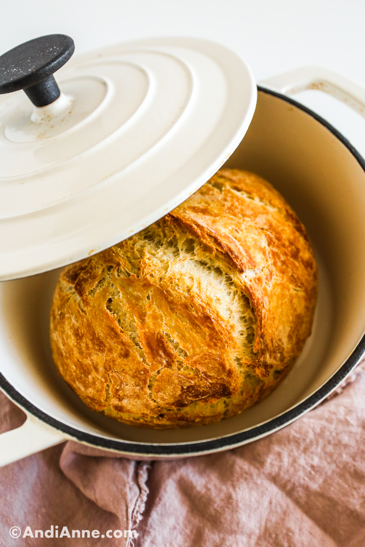 A loaf of bread inside a white dutch oven pot.