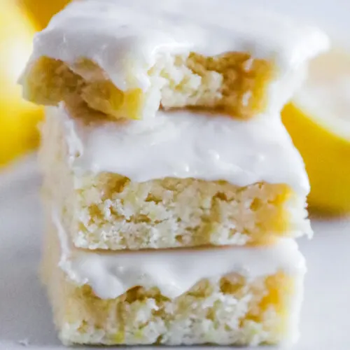 A stack of lemon brownies, one with a bite taken out.