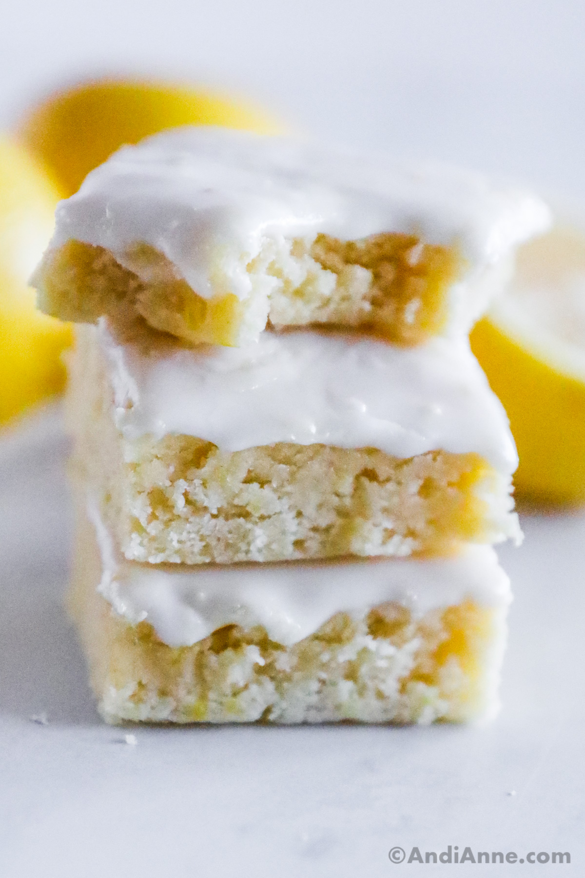 A stack of lemon brownies, one with a bite taken out of it.