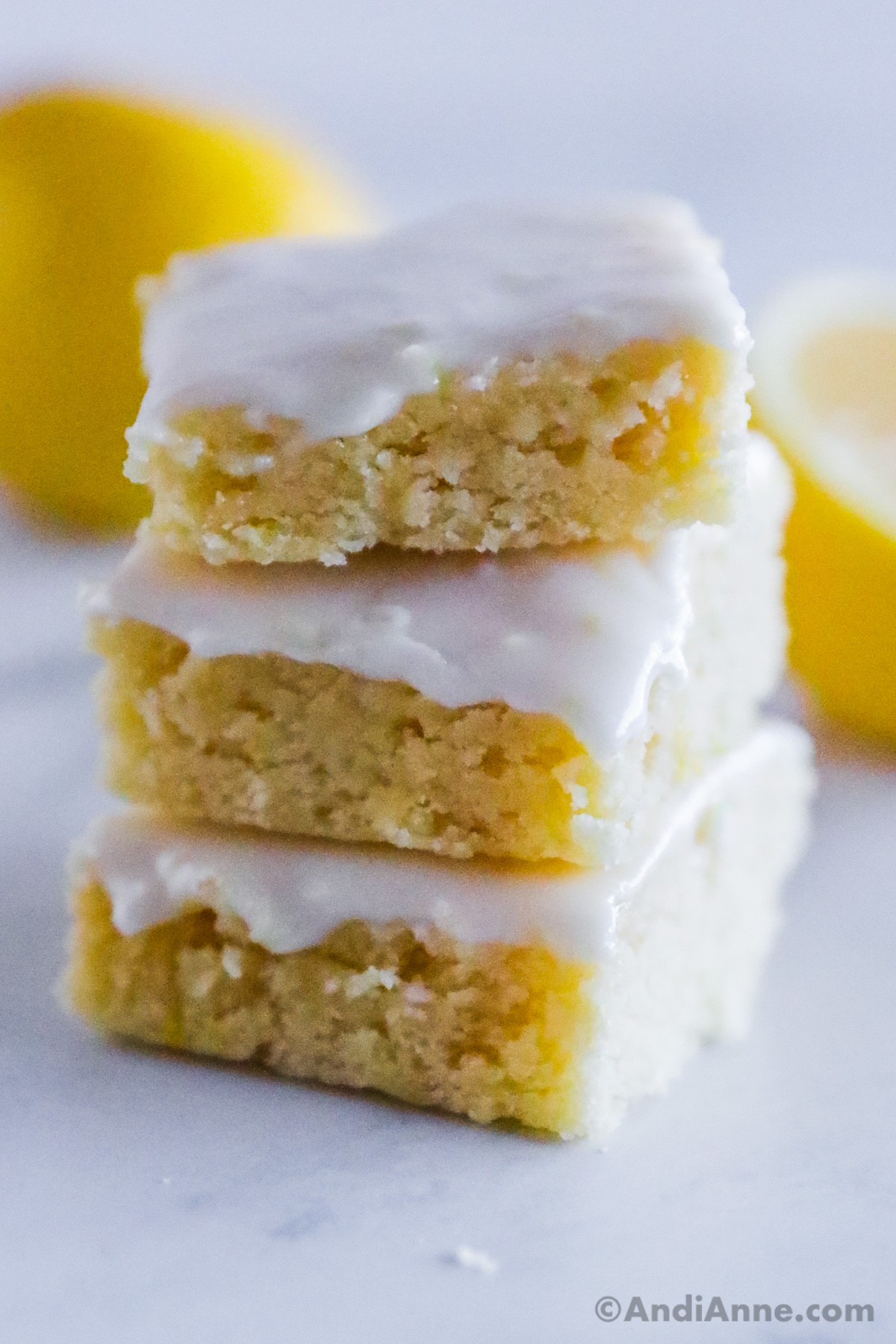 A stack of lemon brownies on top of each other, each topped with glaze. 