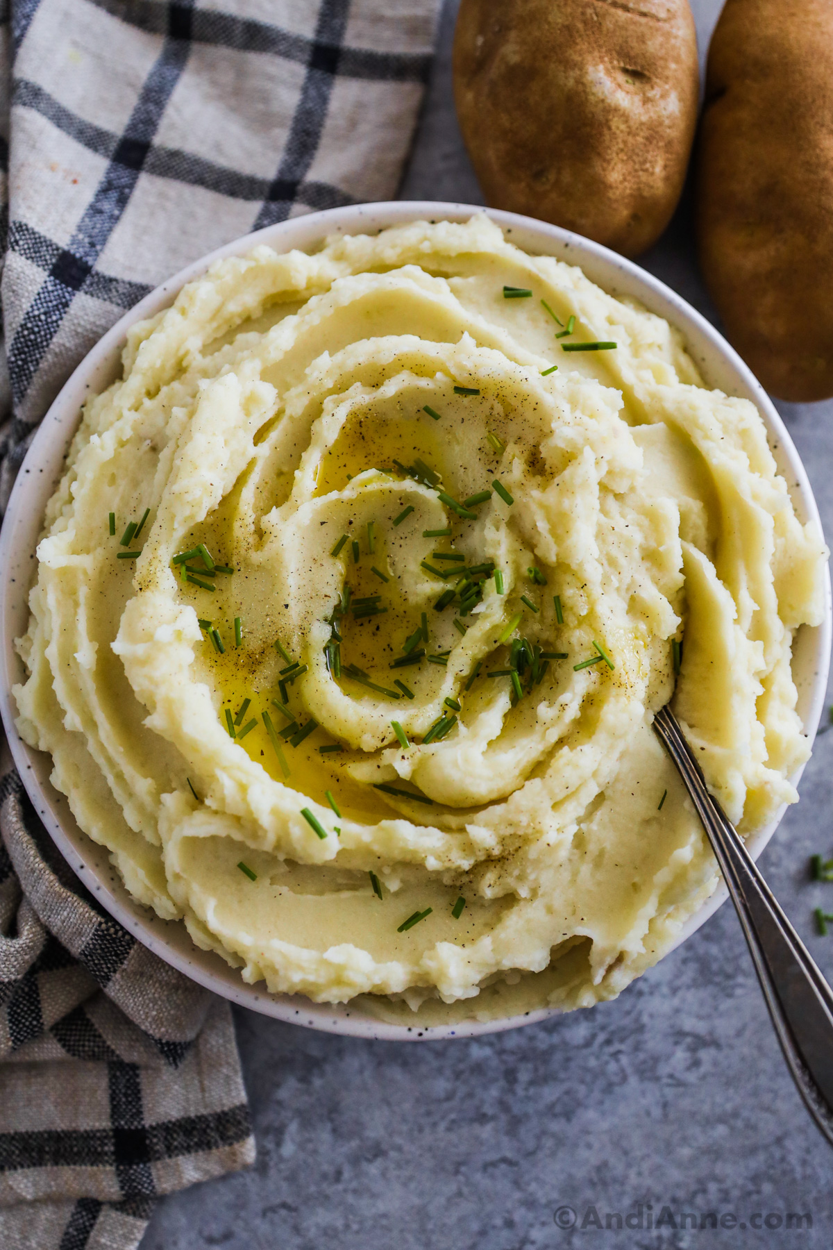 A bowl with creamy plant based mashed potatoes topped with chopped chives.