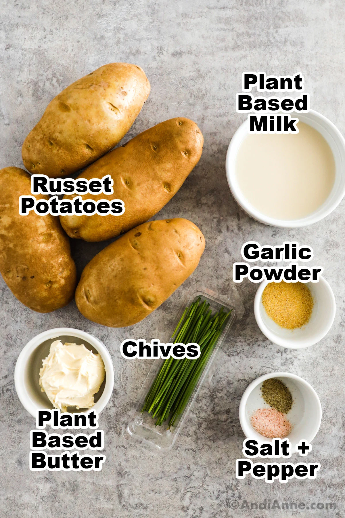 Recipe ingredients on the counter including russet potatoes, and bowls of plant based milk, garlic powder, plant based butter, salt and pepper.