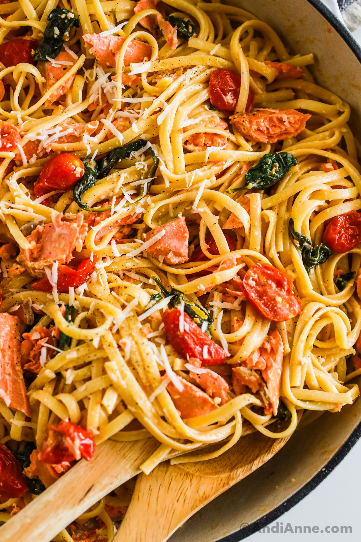Close up of grape tomatoes, spinach, salmon in pasta. 