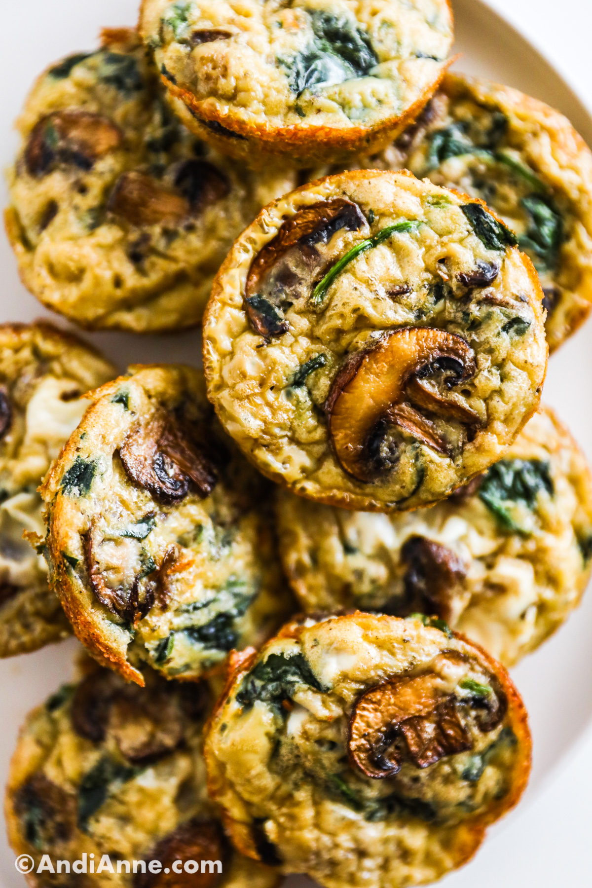 A stack of mushroom spinach quiche muffins on a plate.