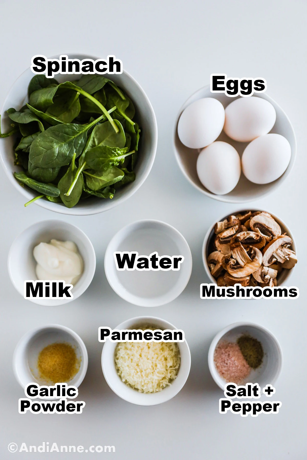 Recipe ingredients in bowls including spinach, eggs, milk, water, parmesan cheese,  mushrooms garlic powder, salt and pepper.