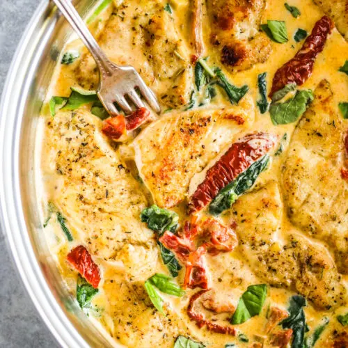 A fork holding sun dried tomato and chicken in creamy tuscan chicken recipe.