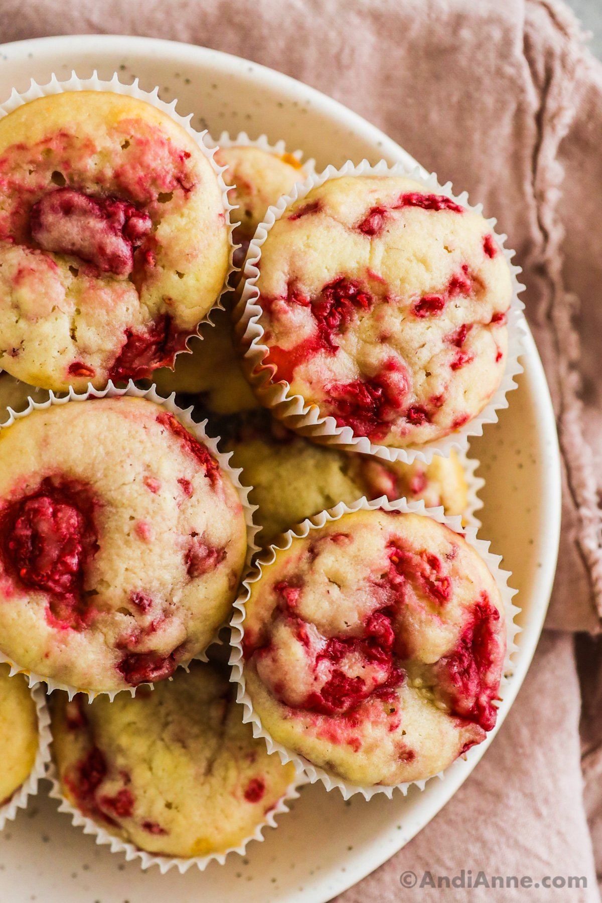 A pile of raspberry muffins on a plate.