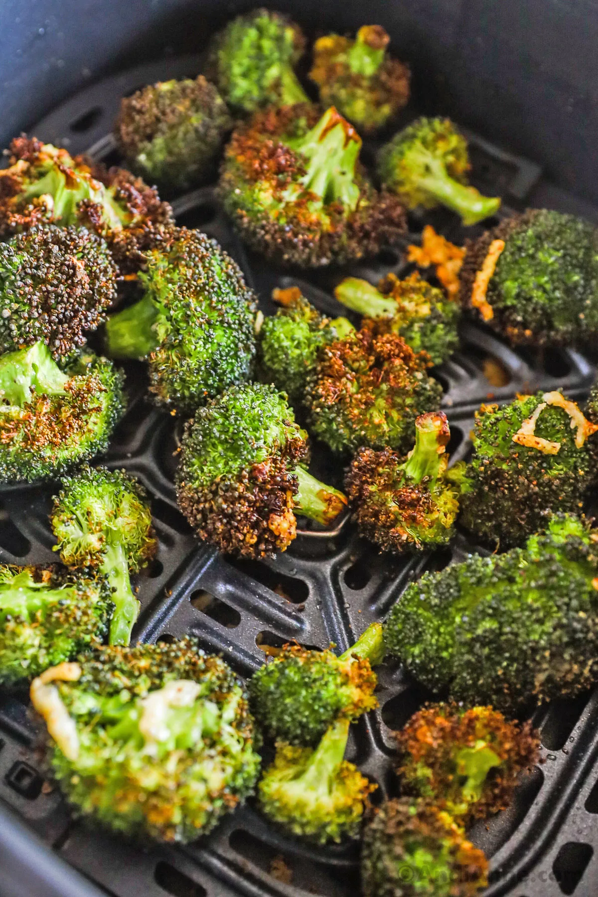 Crispy broccoli florets in an air fryer basket.