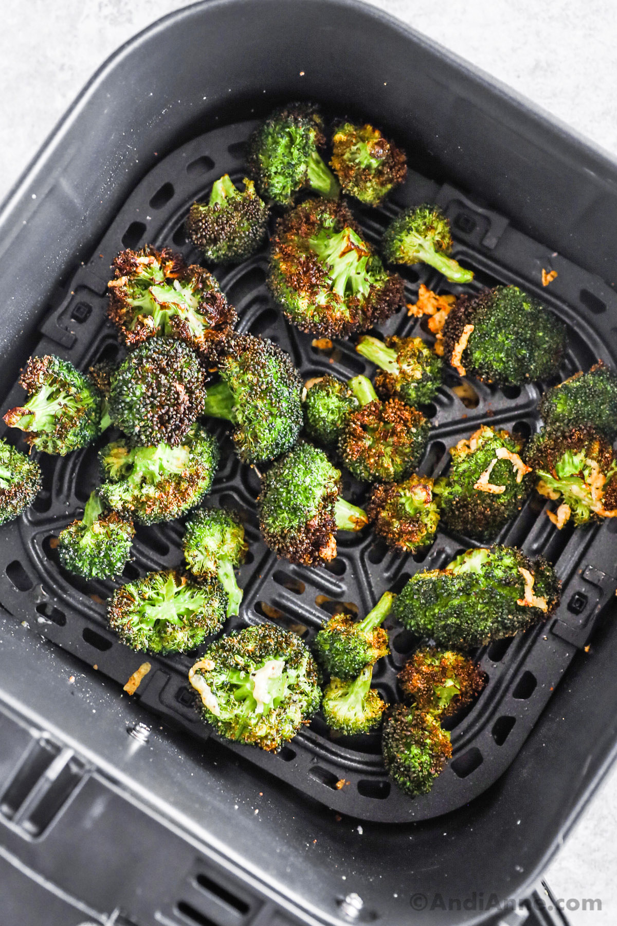 Crispy broccoli in an air fryer basket.