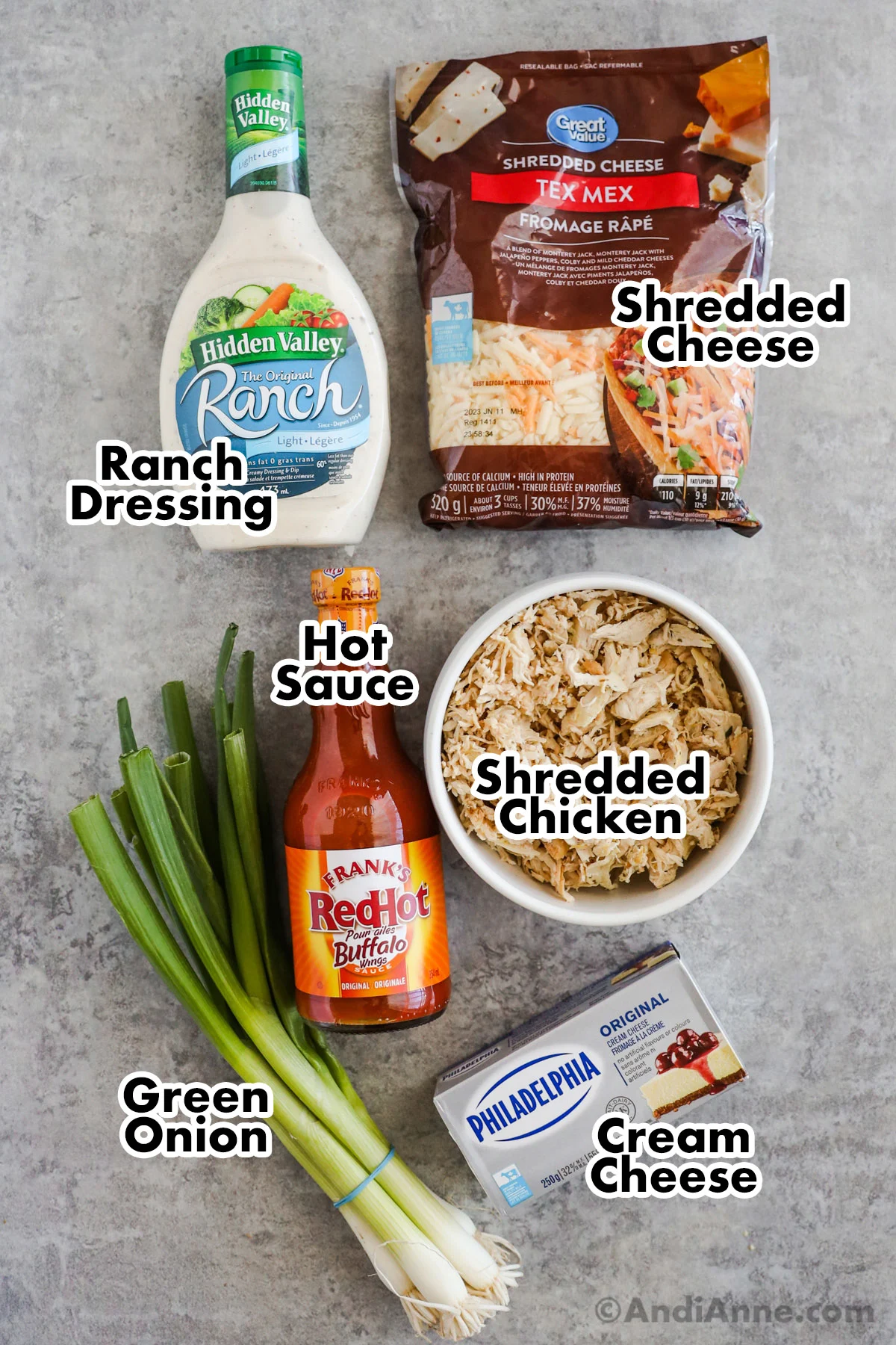 Recipe ingredients on the counter including ranch dressing, shredded cheese, hot sauce, shredded chicken and green onion.