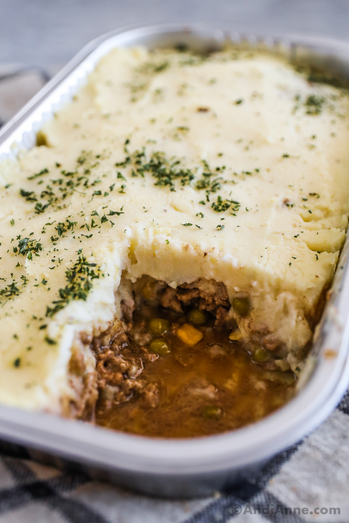 Close up of the layers inside a costco shepherds pie. You can see the top layer is mashed potatoes, and bottom layer is ground beef with peas and corn and a bit of liquid.