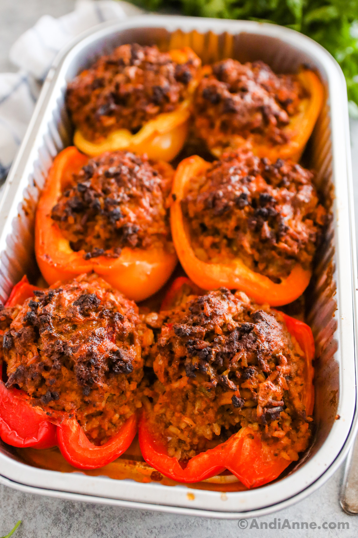 Close up of baked stuffed bell peppers in a foil tray.